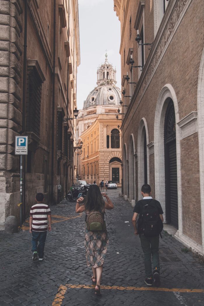 People walking through historic cobblestone streets in Rome, capturing ancient architecture and vibrant culture.
